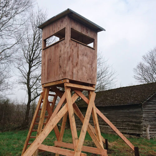 Holzjagdkanzel auf stabilen Stelzen in einer ländlichen Umgebung mit Bäumen
