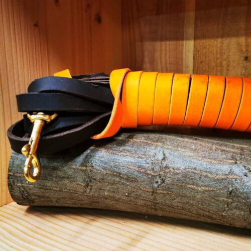 Handgefertigter Schweißriemen aus Fettleder für Jagdhunde auf Holz liegend
